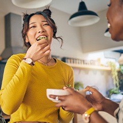 Friends smiling while eating together in kitchen