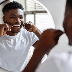 Man smiling while flossing his teeth