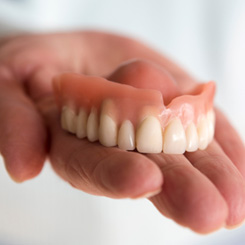 A closeup of a hand holding a removable denture