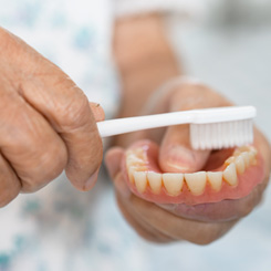 An elderly patient brushing their denture