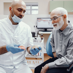 An older man and his dentist discussing dentures