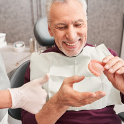 A dentist showing dentures to her older patient