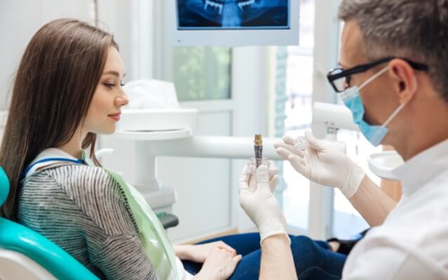 Dental patient discussing the four step dental implant process with dentist