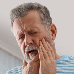 Man with lost filling holding cheek in pain