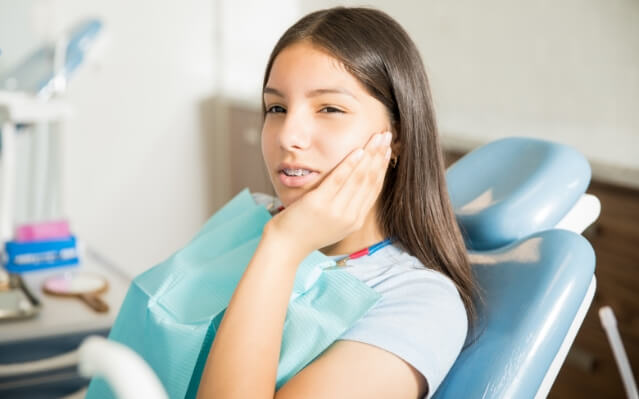 Woman holding cheek during emergency dentistry visit