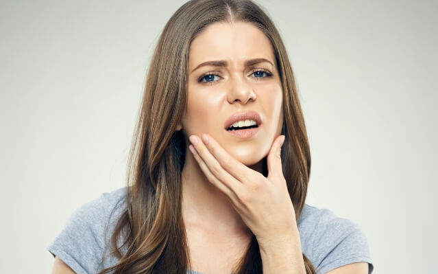 Woman in need of root canal therapy holding jaw in pain