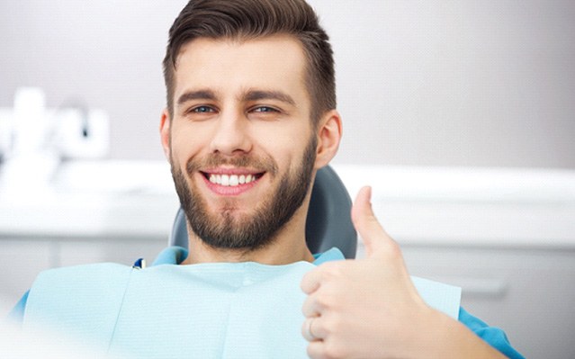 Bearded man in dental chair giving a thumbs up