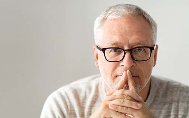 Man wearing glasses with hands on mouth thinking