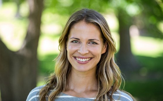 Woman with striped shirt standing outdoors and smiling