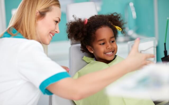 Dental team member talking to young patient during children's dentistry visit