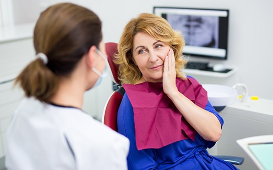 a dental patient touching her cheek in pain