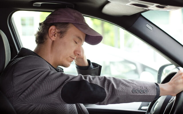 Tired man falling asleep while driving before sleep apnea therapy