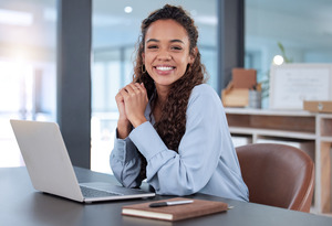 Young businesswoman smiling and sitting at laptop