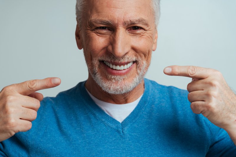 An older man pointing out his lifelike dentures