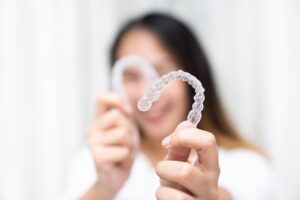 Woman holding up her Invisalign trays